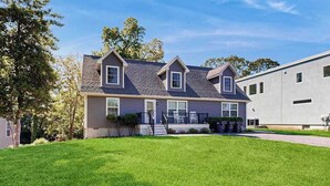 A two-story house with a front porch, a well-maintained lawn, and a large garage. - Rehoboth Beach dog-friendly, hot tub, game room, and Washer/Dryer (Rehoboth Beach)