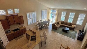 A spacious living area with a dining table, sofa, and kitchen area with cabinets and a countertop. - Grande at Canal Pointe home with pools, sports courts, & gym (Rehoboth Beach)