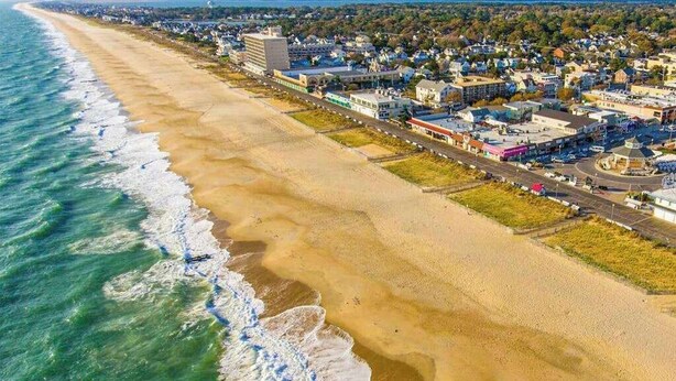 An aerial view of a coastal town with a beach, buildings, and roads. - Grande at Canal Pointe home with pools, sports courts, & gym (Rehoboth Beach)