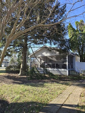 A house with a porch, a large tree in front, and a clear sky. - Town of Rehoboth Beach Dog friendly home with W/D & free WIFI (Rehoboth Beach)