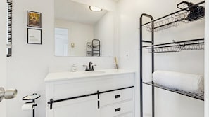 Une salle de bain équipée d’un lavabo, d’un miroir, d’un porte-serviettes et d’une armoire blanche avec des tiroirs.
