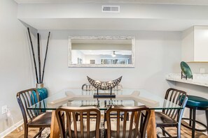A dining area with a glass table, wooden chairs, and a decorative bowl centerpiece. - Eagles Landing - updated condo w/two balconies, WiFi, W/D, & AC - great location (Rehoboth Beach)