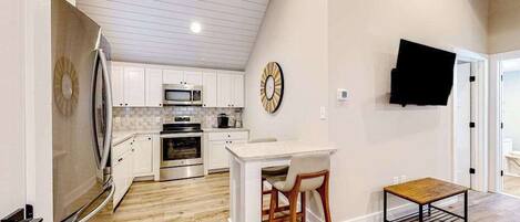 A kitchen with white cabinets, a microwave, and an oven. There is a wooden table and two chairs.