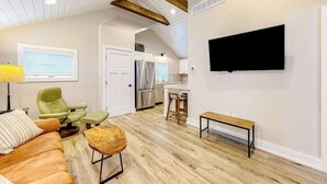 Un salon moderne comprenant un canapé, des fauteuils, une table basse et un téléviseur fixé au mur.