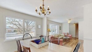 A spacious dining area with a large table, chairs, and a chandelier. There are multiple windows providing natural light and a view of the outside. - Country Manor dog friendly house w/ping pong, deck & balcony (Rehoboth Beach)