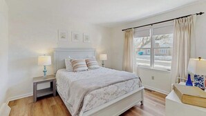 A bedroom with a bed, bedside tables, a window with curtains, and a view of the outside. - Country Manor dog friendly house w/ping pong, deck & balcony (Rehoboth Beach)