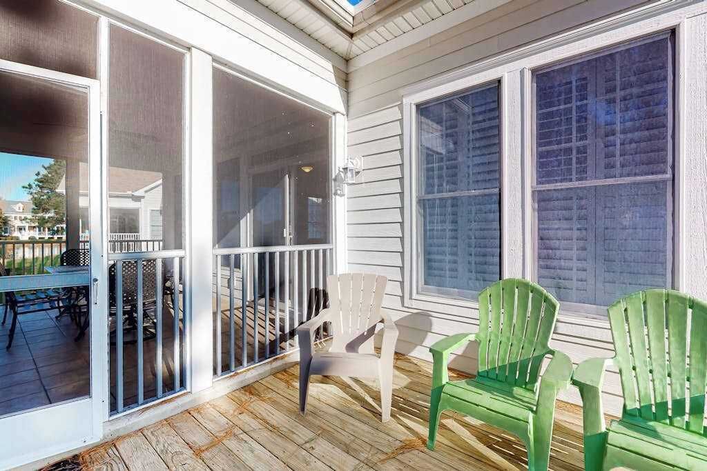 A covered porch with a sliding glass door, a table with chairs, and a view of the backyard.