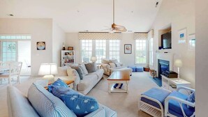 Un salón espacioso con sofá, sillones, una mesa de centro y televisor.