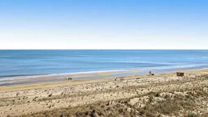Een strand met een heldere lucht, zand en een klein gebouw.