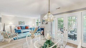 Een woonkamer met een bank, stoelen, een glazen tafel en een kroonluchter.