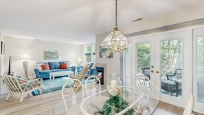 Un salon comprenant un canapé, des fauteuils, une table en verre et un lustre.