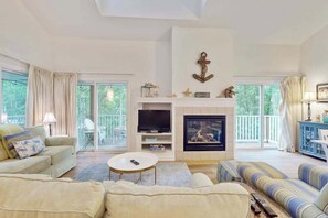 A spacious living room with a fireplace, a television, and a sofa. - Sea Colony condo with pool, hot tub, sauna, fitness room, gas fireplace & deck (Bethany Beach)