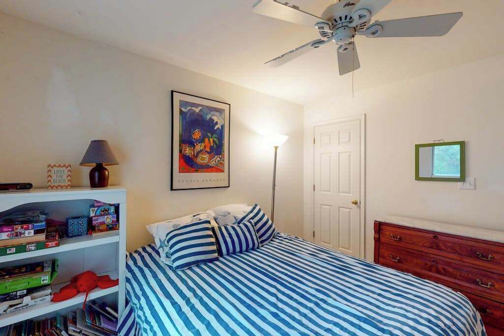 Une chambre à coucher avec un lit, un ventilateur de plafond, une bibliothèque et une porte.