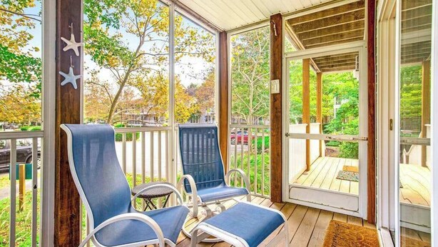 A covered porch with two blue chairs and a wooden deck. - Sea Colony Tennis 1st-floor condo with gym, tennis court, & sauna (Bethany Beach)