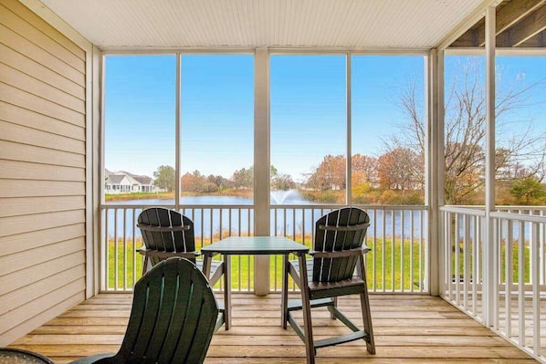 Une véranda abritée donnant sur un lac, deux fauteuils Adirondack et une petite table.