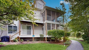 A two-story house with a covered porch, a small garden, and a pathway leading to the house. - Sea Colony Tennis 2nd-floor condo pool & gym (Bethany Beach)