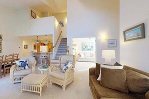 A spacious living area with a high ceiling, a staircase, and a view of a balcony. - Sea Colony Tennis 2nd-floor condo pool & gym (Bethany Beach)