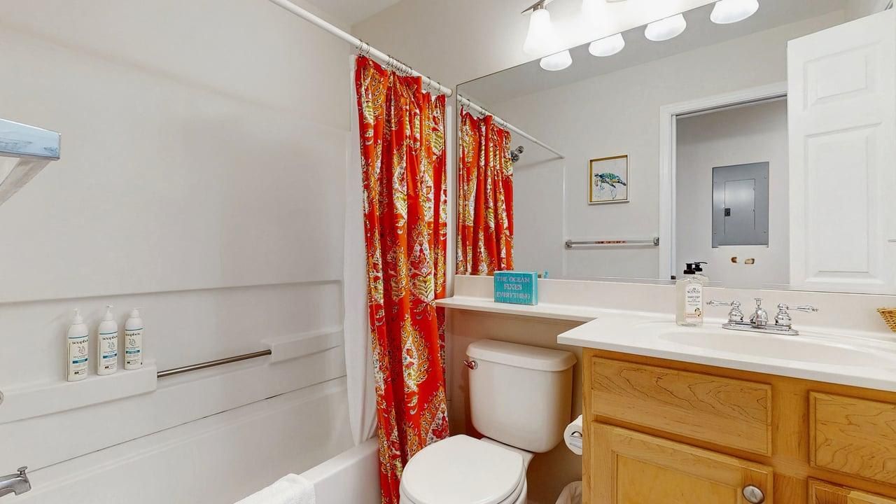 Un baño con bañera, inodoro y tocador con espejo.