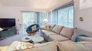 Una sala de estar con sofá, sillón, televisor y una mesita redonda.
