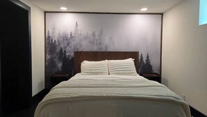 Ein Schlafzimmer mit Bett, Kopfteil, zwei Nachttischen und einer Wandmalerei.