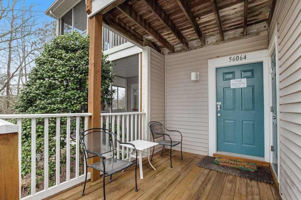 A porch with a white railing, a blue door, and a number 56064 sign.
