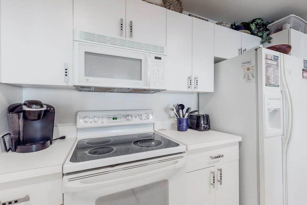 Cocina compacta con microondas, estufa y refrigerador.