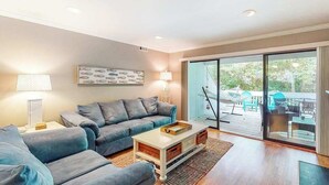 Sala de estar com sofá, mesa de centro e vista para o exterior.