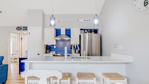 Eine moderne Küche mit einer zentralen Kochinsel, Barhocker und einer Uhr an der Wand.