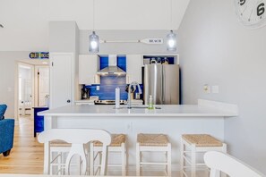 Eine moderne Küche mit einer zentralen Kochinsel, Barhocker und einer Uhr an der Wand.