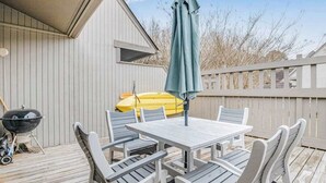 Une terrasse avec une table et des chaises, un barbecue et un kayak.