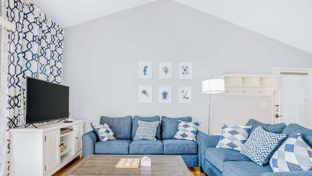 Un salon comprenant un canapé, un téléviseur, une table basse et des œuvres d’art murales.