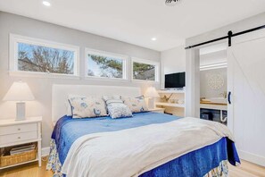 Ein Schlafzimmer mit einem Bett, zwei Nachttischen, einem Fernseher und einem Schreibtisch.