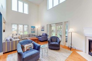 A spacious living room with a sofa set, armchairs, a coffee table, and a fireplace. - Sea Colony Tennis townhouse with fireplace, sauna, pool, & basketball court (Bethany Beach)