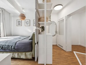 Ein Schlafzimmer mit Bett, Schrank, Spiegel und Deckenleuchte.