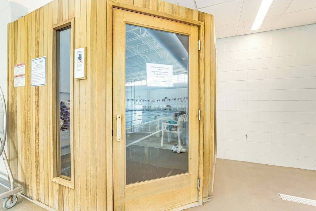 Een houten kamer met een glazen deur, een rolstoel en een bord aan de muur.