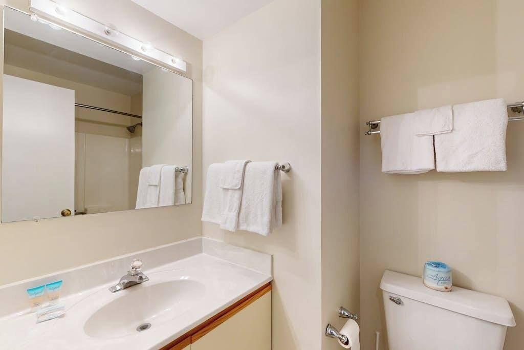 Une salle de bain équipée d’un lavabo, d’un miroir, d’un porte-serviettes et de toilettes.
