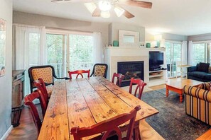 Ein Essbereich mit Holztisch und -stühlen, einem Kamin, einem Fernseher und einer Couch.