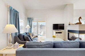 Un salon avec un canapé, un téléviseur, une cheminée et un balcon.