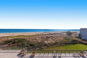 A coastal property with a deck overlooking the beach, a fenced yard, and a house with a sloped roof. - Sea Colony Ocean 3rd floor condo w/ shared sauna, elevator, and gym (Bethany Beach)