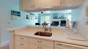 A kitchen with white cabinets, a stainless steel sink, and a countertop with a coffee maker. - Sea Colony Tennis 1st-floor condo with pool & tennis court (Bethany Beach)