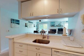 A kitchen with white cabinets, a stainless steel sink, and a countertop with a coffee maker. - Sea Colony Tennis 1st-floor condo with pool & tennis court (Bethany Beach)