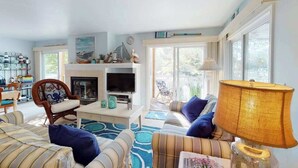 A living room with a fireplace, television, and a large window. - Sea Colony Tennis 1st-floor condo with pool & tennis court (Bethany Beach)