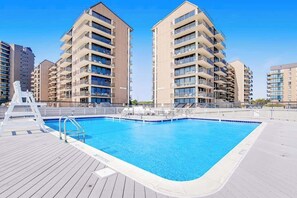 A swimming pool surrounded by modern apartment buildings. - Sea Colony Tennis 1st-floor condo with pool & tennis court (Bethany Beach)