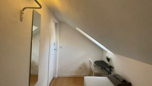 A bedroom with a bed, a desk, a chair, a mirror, and a skylight. - Santos (Lisbon)