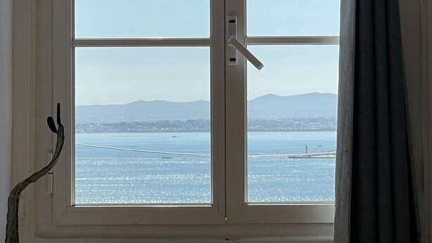A window with a view of a body of water and distant mountains. - Santos (Lisbon)