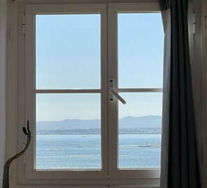 A window with a view of a body of water and distant mountains. - Santos (Lisbon)