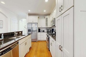 A kitchen with white cabinets, stainless steel appliances, and a wooden floor. - Bayside Resort house w/ central AC, private washer/dryer, (Selbyville)