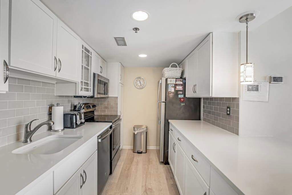 A modern kitchen with white cabinetry, a stainless steel sink, and a microwave.