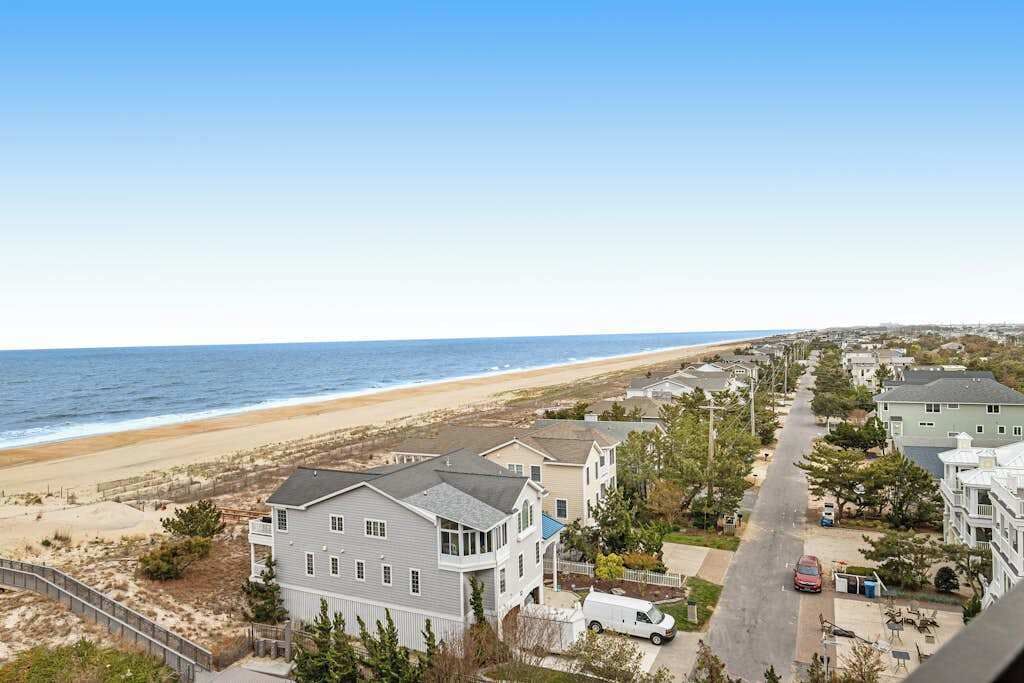 A coastal residential area with houses, a beach, and a clear sky.