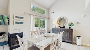 Un comedor con chimenea, una mesa con sillas, un televisor y cuadros en la pared.